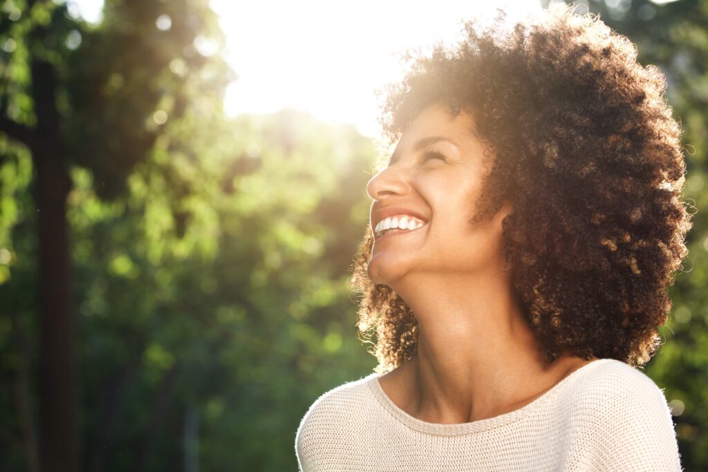 Close up side portrait of beautiful confident woman laughing in nature scaled