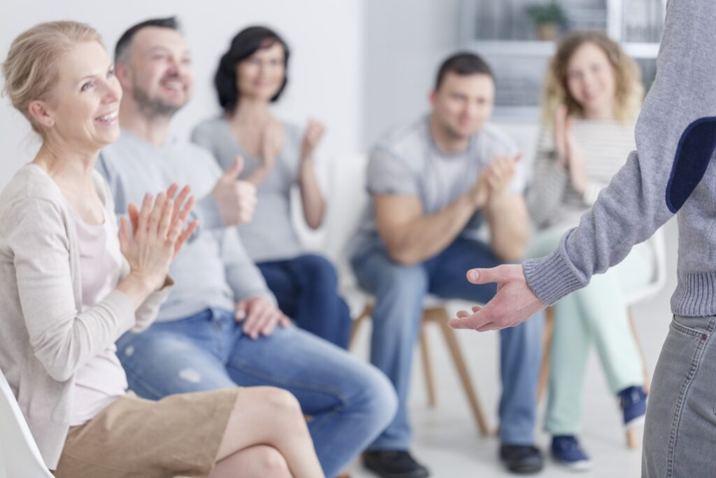 Man standing in front of applauding support group after making progress